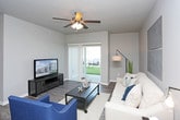 This single-floor residence offers a thoughtfully designed layout with a cohesive neutral color palette of soft grays and warm tones throughout. The living room serves as a central gathering space, featuring durable wood-style flooring, a ceiling fan with light fixture, and a sliding glass door with vertical blinds that provides direct outdoor access and natural light. The kitchen is well-equipped with dark espresso cabinetry, crisp white countertops, stainless steel appliances including a range, microwave, and dishwasher, complemented by wood-style flooring that ties the space together. The primary bedroom is generously sized with plush carpeting, a ceiling fan, and ample room for a sitting area, while a secondary bedroom also offers carpeted floors and a bright window. A dedicated office or flex space features carpet and a large window, offering versatility for various uses. Two full bathrooms are finished with tile flooring, dark vanity cabinetry, white countertops, and tub-shower combinations. Throughout the residence, consistent finishes and neutral tones create a calm, modern ambiance well-suited for comfortable everyday living.