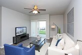 This single-floor residence offers a thoughtfully designed layout with a cohesive neutral color palette of soft grays and warm tones throughout. The living room serves as a central gathering space, featuring durable wood-style flooring, a ceiling fan with light fixture, and a sliding glass door with vertical blinds that provides direct outdoor access and natural light. The kitchen is well-equipped with dark espresso cabinetry, crisp white countertops, stainless steel appliances including a range, microwave, and dishwasher, complemented by wood-style flooring that ties the space together. The primary bedroom is generously sized with plush carpeting, a ceiling fan, and ample room for a sitting area, while a secondary bedroom also offers carpeted floors and a bright window. A dedicated office or flex space features carpet and a large window, offering versatility for various uses. Two full bathrooms are finished with tile flooring, dark vanity cabinetry, white countertops, and tub-shower combinations. Throughout the residence, consistent finishes and neutral tones create a calm, modern ambiance well-suited for comfortable everyday living.