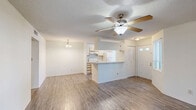 Located in Palm Bay, Florida, this two-bedroom, three-bathroom single-floor residence offers a practical and well-appointed layout. Wood-look flooring runs throughout the home, lending a clean, cohesive look to every room. The open-concept kitchen and living area serves as the heart of the space, featuring a curved peninsula with a sink, white appliances including a range and refrigerator, and white cabinetry. A textured ceiling and multiple windows bring in generous natural light, while a sliding glass door in the living room opens to an outdoor view of lush greenery. A ceiling fan adds comfort to the living area. The bedrooms are well-sized, with the primary bedroom offering corner windows for added brightness and a walk-in closet equipped with wire shelving on both sides for organized storage. A second bedroom connects easily to the hallway. The three bathrooms are finished with wood-look flooring and include vanities with large mirrors and bright vanity lighting. At least one bathroom features a full soaking tub with tiled surround. Natural light filters into the kitchen through a dedicated window, keeping the space bright and airy. This residence combines functional design with a light, neutral palette throughout.