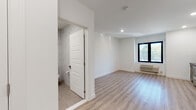 This thoughtfully renovated single-floor unit showcases a clean, contemporary design with consistent light wood-tone flooring and crisp white walls throughout, creating a bright and cohesive aesthetic.

The kitchen is a standout feature, outfitted with two-tone cabinetry — dark charcoal lower cabinets paired with white upper cabinets — all accented with brushed gold hardware. Black countertops, a matte black farmhouse sink, a mosaic tile backsplash, and a full suite of stainless steel appliances, including a range, microwave, dishwasher, and refrigerator, complete this functional and stylish space. A louvered closet door and recessed lighting add practical and polished touches.

The living area is open and airy, benefiting from a large black-framed window that invites natural light and outdoor views. A wall-mounted HVAC unit ensures year-round comfort.

The bathroom is elegantly finished with floor-to-ceiling marble-look tile, a deep soaking tub with a glass enclosure and rainfall showerhead, a dark vanity with a black countertop and gold hardware, a mirrored medicine cabinet, and large-format floor tiles. Every detail reflects a high standard of modern design, making this a well-appointed and move-in-ready space.