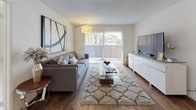 This single-floor residence offers a thoughtfully designed layout with a comfortable and cohesive aesthetic throughout. The living room serves as the heart of the home, featuring warm hardwood-style flooring, a plush area rug, and a large sliding glass door with vertical blinds that floods the space with natural light and provides access to an outdoor area. A sleek media console and bold abstract wall art complete the inviting atmosphere.

The kitchen is well-equipped with stainless steel appliances, including a gas range, built-in microwave, and refrigerator, complemented by rich dark granite countertops and warm maple cabinetry. The adjacent dining area accommodates a solid wood dining table surrounded by upholstered chairs, with natural light streaming through a window framed by views of lush greenery.

The primary bedroom is a serene retreat with plush carpeting, a large window overlooking outdoor foliage, and a mirrored closet. Its en-suite bathroom features dark granite countertops, maple vanity cabinetry, and hardwood-style flooring. The second bedroom offers carpeted floors, a mirrored sliding closet, and a bright window, while a nearby full bathroom mirrors the same quality finishes found throughout the home.