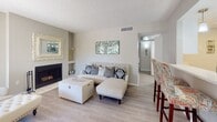 Located at 1050 S Bill Martin Dr in Tucson, Arizona, this single-floor residence offers a thoughtfully designed layout with a clean, neutral palette that creates a cohesive and welcoming atmosphere throughout. The living room serves as the heart of the home, showcasing light wood-look flooring, a textured ceiling, and a striking arched window that invites natural light. A fireplace with built-in shelving anchors the room, adding warmth and architectural character. The kitchen is laid out efficiently with white cabinetry, light stone countertops, stainless steel appliances including a refrigerator and range, and a dishwasher — offering both functionality and style. The bedrooms are carpeted for comfort, each featuring windows with blinds for natural light and privacy. The primary bedroom is generously sized, while the additional bedrooms provide ample space and include closet storage. The primary bathroom is equipped with a walk-in glass shower, white vanity cabinetry, and a granite-style countertop, while a second bathroom offers a clean, functional design with light wood-look flooring. The home's consistent use of soft gray tones, white trim, and light finishes throughout creates a bright, modern, and inviting living environment.