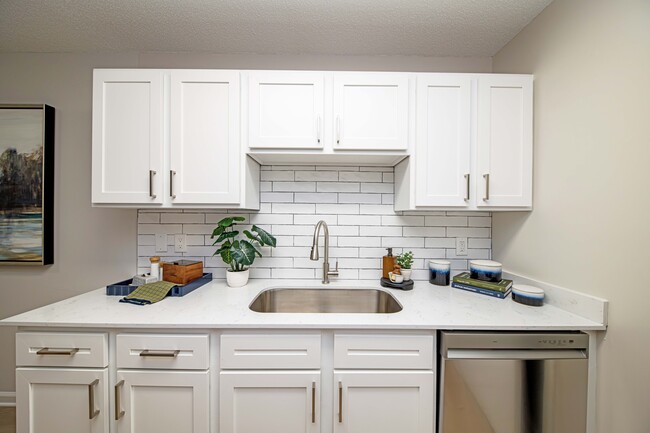 Cocina con encimeras de granito y gabinetes modernos. - The Collins Apartment Homes