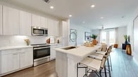 This thoughtfully designed 1-bedroom, 1-bathroom residence offers a seamless open-concept layout across a single floor, blending functionality with contemporary style. The kitchen is a standout feature, showcasing light wood-grain cabinetry, a textured tile backsplash, stainless steel appliances including a refrigerator, range, and over-the-range microwave, and a large island with a deep single-basin sink and bar seating — ideal for casual dining or entertaining. Wood-style flooring flows throughout the main living areas, lending warmth and cohesion. The dining area sits adjacent to the kitchen and connects naturally to the living room, which is bathed in natural light from floor-to-ceiling glass doors that open to a private balcony offering open outdoor views. The generously sized primary bedroom features plush carpeting, a ceiling fan, and ample natural light. The bathroom is clean and modern, with light wood vanity cabinetry, a white quartz countertop, a large framed mirror, and a shower-tub combination. A dedicated closet provides practical storage. Recessed lighting throughout, crisp white walls, and a neutral palette create a bright, airy ambiance across the entire residence.