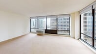 Located at 233 E Wacker Drive in Chicago's sought-after Streeterville neighborhood, this two-bedroom, two-bathroom residence offers a well-designed single-floor layout with impressive city views throughout. Floor-to-ceiling windows in the expansive combined living and dining area flood the space with natural light while framing striking panoramic views of the Chicago skyline. The open layout connects seamlessly to the galley-style kitchen via a pass-through window, which features warm wood cabinetry, dark granite countertops, stainless steel appliances, and hardwood flooring — a functional and stylish hub for cooking and entertaining. Both bedrooms are carpeted and generously sized, with the primary bedroom offering ample room and large windows overlooking the cityscape. The residence includes five closets in total, providing exceptional storage throughout. Two full bathrooms are finished with classic tile surrounds, undermount sinks, and wood vanity cabinetry. A dedicated hallway connects the rooms with ease. The textured ceilings and neutral color palette throughout create a clean, cohesive ambiance, while the abundant natural light and sweeping urban views add a dynamic energy to this well-appointed Chicago residence.