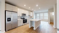 Located at 4902 Cosmos Circle in Wimauma, FL, this two-story home offers 3 bedrooms, 4 bathrooms, and a thoughtfully designed layout spread across two floors. The main floor provides generous living space anchored by an open-concept kitchen and living room. The kitchen is outfitted with white shaker cabinetry, a subway tile backsplash, stainless steel appliances including a side-by-side refrigerator with ice maker, an electric range with over-the-range microwave, and a large center island with quartz countertops — ideal for both meal prep and casual dining. Light wood-tone flooring runs throughout, lending warmth and continuity to the space. The living room benefits from multiple windows fitted with blinds, allowing abundant natural light, and is complemented by a ceiling fan overhead. A staircase connects the two floors, with the upper level housing additional bedrooms. The spacious primary bedroom includes its own bathroom and a walk-in closet with wire shelving for organized storage. The bathrooms throughout feature quartz vanities, brushed nickel fixtures, frameless glass shower enclosures, and matching wood-tone flooring. Three closets total provide ample storage across the home, while the clean, neutral color palette and modern design elements create a bright, cohesive aesthetic throughout.