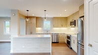 Located at 550 Sheridan Square in Evanston, IL, this thoughtfully designed 3-bedroom, 2-bathroom residence offers a well-appointed single-floor layout with modern finishes throughout. The open-concept living room is a standout, featuring warm hardwood-style flooring, recessed lighting, and a bank of large windows alongside sliding glass doors that lead to a private balcony, filling the space with abundant natural light and views of the surrounding neighborhood. The kitchen is a true highlight, showcasing light wood cabinetry, white quartz countertops, a classic subway tile backsplash, and a full suite of stainless steel appliances including a double oven and dishwasher. Pendant lighting above the central island adds a refined touch. The spacious primary bedroom offers recessed lighting and a window with outdoor views. Additional bedrooms are finished with the same hardwood-style flooring and neutral tones, offering versatile use. The two bathrooms are elegantly appointed — one features a walk-in glass shower with floor-to-ceiling marble-style tile, penny-round mosaic flooring, and brushed gold fixtures, while the second includes a soaking tub with matching marble-style tile surround. Recessed lighting and hexagonal tile flooring complete the clean, contemporary aesthetic throughout.