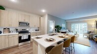 This well-appointed 2-bedroom, 2-bathroom residence in Inver Grove Heights, MN offers a thoughtfully designed single-floor layout that maximizes comfort and functionality. The open-concept living area is bright and welcoming, featuring wood-style flooring, a neutral color palette, and a sliding glass door that opens to a private balcony with outdoor views, flooding the space with natural light.

The modern kitchen is a standout feature, showcasing light wood cabinetry, white quartz countertops, a subway tile backsplash, and stainless steel appliances including a range, microwave, and refrigerator. A large center island with seating provides an ideal space for casual dining and entertaining.

The living room offers a calming atmosphere with a soft sage accent wall, wood-style floors, and direct balcony access. Both bedrooms are carpeted and serene, with the primary bedroom offering generous proportions, a ceiling fan, and windows that bring in natural light. Each bedroom is complemented by a dedicated closet with wire shelving.

The two bathrooms mirror the home's modern aesthetic, featuring light wood vanities, white countertops, wood-style flooring, and clean white finishes. One bathroom includes a walk-in shower. Throughout the residence, consistent design choices create a cohesive, contemporary feel.