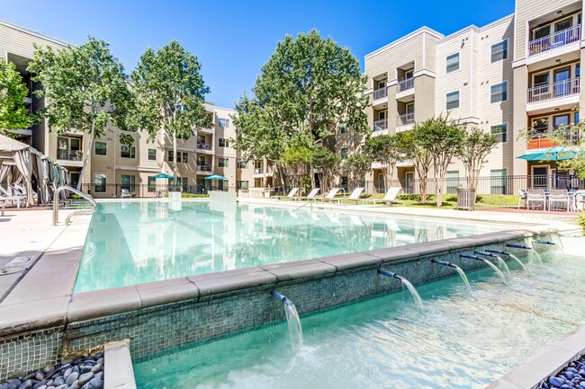 Piscina estilo resort y área de parrilla para barbacoa - District at Medical Center Apartments