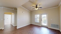 Located at 1402 Shady Ln in Burkburnett, TX, this single-story residence offers a thoughtfully designed layout with 2 bedrooms and 2 bathrooms. The living room makes a strong first impression with its elegant tray ceiling, crown molding, ceiling fan with light fixture, and rich wood-style flooring. Natural light fills the space through a large window and a glass-paned door that opens directly to a private balcony, providing outdoor access and views of the surrounding area. The kitchen features dark espresso cabinetry, granite-style countertops, a double-basin sink, pendant lighting, and black appliances, including a full-size refrigerator. A hallway connects the kitchen to the rest of the unit, with additional storage and utility access nearby. Both bedrooms are carpeted and include ceiling fans and windows with blinds that allow natural light while maintaining privacy. The primary bedroom includes dedicated closet space and its own en-suite bathroom, which boasts a dual-sink vanity with dark wood cabinetry, granite-style countertops, a large mirror, and a walk-in shower. The second bathroom features a full shower-tub combination with marble-style surround panels. Wood-style flooring extends through the main living areas, tying the home together with a consistent, warm aesthetic throughout.