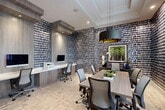 Located at 11181 W 35th Way in Hialeah, FL, this thoughtfully designed amenity space spans a generous single floor and offers a diverse range of functional areas to suit both work and leisure. The grand lobby welcomes visitors with large-format white tile flooring, a coffered tray ceiling accented in yellow, bold geometric drapes in green and gold, and an eye-catching starburst chandelier. Abundant natural light streams through floor-to-ceiling windows and glass doors that open to the outdoors, enhancing the airy, upscale atmosphere. A gallery-style hallway connects the various areas, featuring large-scale framed artwork, porcelain tile flooring, and a pendant light fixture beneath a cheerful yellow tray ceiling. The business center is a standout room, dressed in bold navy-and-white patterned wallpaper with built-in workstations, computer monitors, and a central conference table surrounded by ergonomic seating — ideal for productivity. A private office adjacent to the business center offers a quiet, focused workspace with natural light and glass-paneled doors. The game room delivers a dynamic contrast, boasting a geometric mural in black, yellow, and white, striped carpeted flooring, an arcade machine, a shuffleboard table, a wall-mounted TV, and casual bistro seating — creating an energetic, entertainment-focused environment.