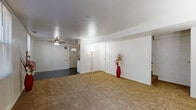 Located at 210 W Heatherwood Dr in Barberton, Ohio, this two-floor home offers a practical and comfortable layout designed for everyday living. The main living area is generously sized, featuring warm neutral carpet, crisp white walls, and a ceiling fan overhead. A front entryway with a classic paneled door and arched window detail welcomes you inside, opening naturally into the living space. The kitchen is equipped with warm wood cabinetry, granite-style countertops, a gas range, and a full-size refrigerator, all set against a dark, polished floor and painted brick accent walls that lend a sturdy, utilitarian character. An adjacent open area transitions between hard flooring and carpet, offering flexibility as a dining or multipurpose space bathed in natural light from multiple windows. The bedrooms are each carpeted and bright, with ceiling fans and windows that frame views of the surrounding greenery. Several rooms feature painted brick walls, adding a distinctive textural element throughout. Closet space is present in the bedrooms, and the overall floor plan, as seen in the dollhouse view, reflects a well-organized, multi-room layout across both levels. The home's clean, neutral palette provides a versatile canvas ready for personalization.