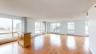 Located in the heart of downtown Montréal, this studio offers a thoughtfully designed open-concept layout that maximizes every square foot. The main living area is bathed in natural light, courtesy of multiple large windows that frame impressive panoramic views of the Montréal skyline. Warm hardwood flooring flows throughout, complementing the bright, white walls and textured ceiling for a clean, contemporary aesthetic. Exposed concrete columns add an industrial character to the space.

The kitchen is well-appointed, featuring warm wood cabinetry with frosted glass inserts, granite countertops, stainless steel appliances including a refrigerator, range, and microwave, and a white tile backsplash. A central island with a granite countertop provides additional prep space and casual dining. The kitchen also benefits from its own city-facing window, keeping the area naturally lit.

A bright, clean hallway with hardwood flooring connects the main living space to the bathroom and additional storage. The bathroom is finished with large-format ceramic tile flooring and wall surround, and includes a full bathtub with shower combination. The spacious closet area off the sleeping zone adds practical storage. This well-located studio offers a functional, light-filled urban retreat in the core of Montréal.