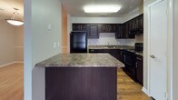 Located at 1916 Sam Rittenberg Blvd in Charleston, SC, this single-floor unit offers a well-designed, open-concept layout that seamlessly connects the main living areas. The living room is generously sized, featuring plush carpeting, a ceiling fan, and a classic fireplace framed by a clean surround — an ideal focal point for the room. Multiple windows allow natural light to filter in throughout the space.

The kitchen is thoughtfully appointed with rich, dark espresso cabinetry, granite-style countertops, black appliances, and hardwood-style flooring. A peninsula counter provides additional prep space and a natural transition into the living and dining areas.

The bedrooms are carpeted and well-proportioned, each equipped with a ceiling fan and windows that bring in natural light. One bedroom features direct access to a private bathroom and a closet, offering added convenience.

Two full bathrooms serve the unit, both consistently finished with dark vanity cabinetry, granite-style countertops, tub-shower combinations, and hardwood-style flooring. Textured ceilings are present throughout the unit, contributing to its classic character. Overall, the space delivers a cohesive, functional layout well-suited for comfortable everyday living in the heart of Charleston.