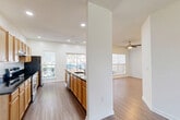 Located at The Martin in Martinsburg, WV, this single-story, two-bedroom, two-bathroom residence offers a well-designed layout with a comfortable and functional flow throughout. The open-concept kitchen and living area serves as the heart of the home, where warm honey-toned cabinetry, dark granite countertops, stainless steel appliances, and a peninsula island create a practical and inviting cooking space. Recessed lighting and multiple windows flood the area with natural light, while hardwood-style flooring extends seamlessly into the adjacent living room, which features a ceiling fan and views to the outdoors. The spacious primary bedroom is generously sized, finished with soft carpeting for added comfort. The second bedroom also features plush carpet and a closet with built-in shelving. Both bathrooms are appointed with warm wood-toned vanities, white countertops, large mirrors, and hardwood-style flooring. A dedicated in-unit laundry room with side-by-side washer and dryer adds everyday convenience. Clean white walls, recessed lighting, and consistent flooring choices throughout give the space a cohesive, move-in-ready feel. A connecting hallway ties all rooms together efficiently, completing this well-appointed single-level home.