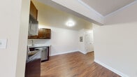 This single-floor residence on Colonnade Drive in Charlottesville, Virginia offers a well-organized layout connecting living, kitchen, and sleeping areas through a cohesive design. Rich, dark hardwood-style flooring runs throughout the main living and kitchen spaces, adding warmth and visual continuity.

The kitchen is a functional galley-style space equipped with stainless steel appliances, including a refrigerator, electric range, microwave, and dishwasher. Dark espresso cabinetry is paired with granite-look countertops and a white subway tile backsplash, creating a clean, modern aesthetic. The open transition between the kitchen and living area promotes an easy flow throughout the space.

The living area is bright and open, anchored by a large sliding glass door fitted with vertical blinds that allow natural light in and provide access to an outdoor area with exterior views. Crown molding adds a refined touch to the main living space.

The bedroom features plush carpeting, a ceiling fan with light fixture, a window with blinds, and access to a spacious walk-in closet with built-in shelving. The bathroom includes a vanity with a white countertop, dark cabinetry, a framed medicine cabinet mirror, and brushed nickel fixtures throughout.