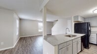 Located at 6049 Rings Ave in Grove City, Ohio, this two-story home offers a clean, modern interior with a well-considered layout across both levels. The main floor features an open-concept living area with durable wood-look plank flooring throughout, neutral gray walls, and a textured ceiling. A peninsula-style kitchen anchors the space, showcasing gray shaker cabinetry, granite-look countertops, a stainless steel sink, and black appliances including an electric range with over-the-range microwave and a full-size refrigerator. The peninsula provides a natural division between the kitchen and the living area while maintaining an open feel. A half bathroom on the main level includes matching cabinetry and countertops consistent with the kitchen's finishes. A staircase leads to the upper level, where plush carpeting runs throughout the bedrooms. Each bedroom offers natural light through blinds-covered windows, and at least one room includes a closet with a hanging rod. The upper-level full bathroom features a soaking tub and shower combination with chrome fixtures. Additional bedrooms on this floor provide flexible use of space. Throughout the home, the consistent use of neutral tones, updated finishes, and practical flooring choices create a cohesive and move-in-ready environment.