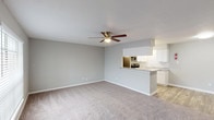 This single-floor unit features a thoughtfully designed open-concept layout that seamlessly connects the living area to the kitchen. The spacious living room is finished with plush carpeting and a ceiling fan with integrated lighting, contributing to a comfortable and functional atmosphere. Neutral gray walls throughout provide a clean, modern backdrop adaptable to a variety of décor styles.

The kitchen is well-equipped with stainless steel appliances, including a refrigerator, range, and microwave. White shaker-style cabinetry extends to the upper and lower levels, offering ample storage, while granite-style countertops add a polished touch. Wood-look flooring runs through the kitchen, providing easy maintenance in this high-use area. A peninsula counter serves as a natural divider between the kitchen and living space.

The bedroom is generously sized, featuring soft carpeting, a ceiling fan, and a large window with blinds that invites natural light. Two closets, including a walk-in, provide substantial storage capacity.

The bathroom is finished with a granite-top vanity with white cabinetry, a framed mirror, and a tub/shower combination with full tile surround and a built-in niche. Wood-look tile flooring completes the space with a cohesive, updated aesthetic.