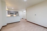Located at 3155 S Vaughn Way in Aurora, Colorado, this one-bedroom, one-bathroom unit offers a thoughtfully designed open-concept layout that maximizes its efficient footprint. Light wood-style flooring flows continuously throughout the space, complemented by crisp white walls and dark wood baseboards that add a clean, modern contrast.

The kitchen serves as a central feature, equipped with gray shaker-style cabinetry, stainless steel appliances including a refrigerator, range, microwave, and dishwasher, and a white peninsula countertop that doubles as a natural divider between the kitchen and living area. Recessed lighting and a wall-mounted sconce provide warm, layered illumination.

The living area is open and airy, benefiting from a large window that invites natural light and offers outdoor views. The bedroom is a well-proportioned private retreat featuring its own window with outdoor views, a wall-mounted climate control unit, and a sliding double-door closet for ample storage.

The bathroom is clean and contemporary, appointed with light wood-style tile flooring, a sliding glass-door walk-in shower with chrome fixtures, and a toilet, all finished in neutral tones. The entry area includes a double-door closet, providing additional storage convenience. Overall, the unit presents a bright, modern, and functional living environment.