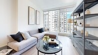 Located in the heart of Ottawa at 180 Metcalfe Street, this well-appointed one-bedroom, one-bathroom unit offers a thoughtfully designed open-concept layout across a single floor. Light hardwood flooring runs throughout, creating a warm, cohesive aesthetic that ties each space together seamlessly.

The kitchen is outfitted with stainless steel appliances, including a full-size refrigerator, electric range, built-in microwave, and dishwasher. Two-tone cabinetry — combining white upper cabinets with light wood lower drawers — is complemented by a white subway tile backsplash and light quartz countertops, creating a clean, modern look.

The dining area is anchored by a striking multi-tiered crystal chandelier that adds an elegant focal point to the space. The living room benefits from floor-to-ceiling windows that flood the room with natural light and frame panoramic views of Ottawa's downtown skyline.

The bedroom is a serene retreat, featuring large windows that continue the city views, a built-in closet, and a calm, neutral palette. The bathroom is finished with large-format marble-effect floor tiles, a glass-enclosed shower, and a sleek floating vanity, delivering a refined, spa-like feel.