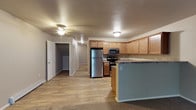 This two-floor residence offers a well-designed layout with functional living spaces throughout. The main level centers around an open-concept kitchen and living area, where light wood-style flooring flows seamlessly between the two spaces. The kitchen is fully equipped with stainless steel appliances — including a refrigerator, range, microwave, and dishwasher — complemented by warm light wood cabinetry, granite-style countertops, and a peninsula that provides additional workspace and casual seating. The living area features a ceiling fan and baseboard heating, with access to an outdoor patio through a sliding glass door that invites natural light. A half bathroom with a vanity, granite-style countertop, and wood cabinetry is also found on this level. The lower level includes carpeted bedrooms, one of which features a closet with wire shelving. A full bathroom on this level offers a tub-shower combo, wood vanity with granite-style countertop, and additional overhead cabinetry. A dedicated laundry room houses a full-size washer and dryer alongside a water heater and wire shelving for storage. The attached garage provides secure parking and extra storage space with a concrete floor and automatic door opener.