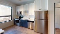 Located at 2717 Fourth St SE in Minneapolis, Minnesota, this modern single-floor residence offers a thoughtfully designed layout with clean lines and contemporary finishes throughout. The living area is bright and inviting, featuring light hardwood-style flooring, track lighting, and a large window that frames views of the surrounding neighborhood, filling the space with natural light. The kitchen is outfitted with stainless steel appliances including a full-size refrigerator, electric range, built-in microwave, and dishwasher. Crisp white upper cabinetry is paired with deep navy lower cabinets, complemented by a subway tile backsplash and light countertops that create a clean, modern aesthetic. The bedroom includes a dedicated nook ideal for a home office setup, along with generous closet space featuring sliding mirrored doors, wire shelving, and ample storage capacity. The hallway connects the living and sleeping areas seamlessly, maintaining an open and efficient flow. The bathroom is finished with a navy vanity, white quartz countertop, undermount sink, modern chrome fixtures, and a large mirror with overhead lighting. A walk-in shower adds further functionality to this well-appointed space. Consistent light wood flooring and a neutral color palette unify the interior, creating a cohesive and modern living environment.