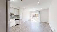 Located at 165 N Hoover St in Los Angeles, this modern 2-bedroom, 2-bathroom unit offers a thoughtfully designed open-concept layout with clean lines and contemporary finishes throughout. Light gray laminate flooring flows seamlessly across every room, complementing the crisp white walls and recessed lighting that create a bright, airy atmosphere.

The kitchen is a standout feature, equipped with stainless steel appliances including a gas range, dishwasher, and a side-by-side refrigerator. White shaker-style cabinetry with sleek hardware extends to the ceiling for ample storage, while a mosaic tile backsplash in soft blue and gray tones adds a stylish accent. The open layout connects the kitchen directly to the living area, which benefits from natural light and sliding glass door access to a private balcony.

Both bedrooms are well-proportioned and bright, each featuring sliding glass doors or windows that invite natural light and outdoor views. The primary bedroom offers a comfortable footprint ideal for a full furniture arrangement. The two bathrooms are finished with floor-to-ceiling linear stone-look tile surrounding deep soaking tubs with shower combinations, paired with wood-tone flooring for warmth. A dedicated closet provides additional storage, completing this well-appointed Los Angeles residence.