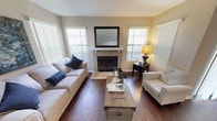 This single-floor residence offers a thoughtfully designed layout with a consistent neutral color palette and a comfortable, welcoming ambiance. The living room serves as the focal point of the home, anchored by a stone-surround fireplace topped with a classic mantle and framed by multiple windows dressed in vertical blinds that allow ample natural light. Rich hardwood-style flooring runs throughout the main living areas, adding warmth and depth to the space.

The kitchen is well-equipped and features crisp white cabinetry, granite countertops, stainless steel appliances, and a peninsula with a built-in sink — ideal for both cooking and casual dining. A sliding glass door connects the kitchen area to an outdoor space, enhancing the sense of openness.

Adjacent to the kitchen, the dining area accommodates a full dining table set beneath a ceiling fan with integrated lighting, and is positioned near the front entry.

The bedrooms are carpeted for comfort and offer generous proportions, with each room providing ample closet space. The primary bedroom is particularly spacious, exuding a calm, restful atmosphere.

The bathrooms are clean and functional, featuring granite-topped vanities with white cabinetry and tub-shower combinations, maintaining the home's cohesive and polished design throughout.