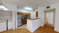 This single-floor residence offers a well-designed open-concept layout that seamlessly connects the main living areas. The kitchen is a functional highlight, featuring warm honey-toned cabinetry, dark granite countertops, and a full suite of stainless steel appliances, including a gas range, built-in microwave, and refrigerator. Light ceramic tile flooring runs throughout the kitchen area, while wood-look flooring extends across the living and dining spaces, creating a cohesive and easy-to-maintain interior.

A peninsula-style breakfast bar separates the kitchen from the dining area, which is accented by a pendant chandelier overhead. The living room is generously proportioned, bathed in natural light from a large sliding glass door that opens to a private balcony overlooking greenery. A ceiling fan adds comfort to this space.

Conveniently located near the kitchen is a dedicated in-unit laundry closet housing a full-size washer and dryer. The bathroom features light ceramic tile flooring and includes a grab bar for added accessibility. A front entryway with tile flooring transitions smoothly into the main living area, completing this practical and well-appointed single-level residence.
