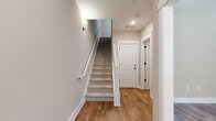 This three-story residence boasts 1,470 square feet of thoughtfully designed living space. The home's layout includes four bedrooms, two bathrooms, and a variety of functional areas spread across three floors. The ground floor, covering 270 square feet, likely houses common areas. The first floor expands to 580 square feet, while the top floor offers the most space at 620 square feet.

The property features a generously sized primary bedroom of 210 square feet, providing a luxurious retreat for the homeowners. The open-concept kitchen and living room create a seamless flow for entertaining and daily life. Three hallways throughout the home ensure easy navigation between spaces.

The interior showcases modern finishes, as evidenced by the image of a staircase area. Light-colored walls, crisp white trim, and warm wood-look flooring create a bright and inviting atmosphere. The staircase, with its white spindles and handrail, adds architectural interest while maintaining an airy feel. Recessed lighting and wall sconces provide layered illumination, enhancing the home's welcoming ambiance.

With its spacious layout and contemporary design elements, this home offers a harmonious blend of comfort and style for its occupants.