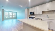 Located at 710 Vikings Parkway in Eagan, MN, this 1-bedroom, 1-bathroom residence offers a thoughtfully designed open-concept layout with modern finishes throughout. Light wood-tone flooring runs through the main living areas, creating a bright and cohesive aesthetic.

The kitchen is a standout feature, equipped with crisp white shaker cabinetry, a subway tile backsplash, quartz countertops, and a full suite of stainless steel appliances including a gas range, built-in microwave, dishwasher, and refrigerator. A peninsula with additional counter space connects the kitchen to the living area, making it ideal for both cooking and entertaining.

The living room is filled with natural light from large floor-to-ceiling windows and offers direct access to a private balcony with views of the surrounding community. The bedroom features plush carpet flooring, a generous closet, and a large window that brings in ample daylight. Two closets provide convenient storage throughout the unit.

The bathroom is finished with a white vanity topped with quartz, tile-surround soaking tub and shower, and wood-tone flooring that ties into the overall design. Clean lines, neutral tones, and contemporary fixtures give the entire space a fresh, modern character.