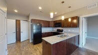 Located at 2833 Kearney Creek Ln in Lexington, KY, this single-floor unit offers a thoughtfully designed layout with consistent finishes throughout. The kitchen serves as a central highlight, featuring rich dark wood cabinetry extending to the upper walls, granite-style countertops, and wood-look flooring. A peninsula with an undermount sink and pendant lighting overhead provides both functional workspace and a natural dividing point between the kitchen and adjoining areas. Black appliances, including a refrigerator, range, and over-the-range microwave, complete the kitchen setup. Recessed lighting supplements the pendant fixtures for thorough illumination.

The bedrooms are finished with neutral-toned carpet and soft gray walls, creating a calm atmosphere. Each room is equipped with a ceiling fan and benefits from natural light through windows with views of the surrounding neighborhood. One bedroom features two closets and direct access to the bathroom, lending it a primary suite-like configuration.

The bathroom is notably spacious, finished with wood-look flooring and a granite-topped dark wood vanity. It includes accessibility features such as grab bars near the toilet and walk-in shower area, making it a practical and inclusive space. The overall layout, visible in the 3D overview, presents a compact yet functional floor plan with well-defined living zones.