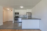 Located at 3101 Eglinton Ave E in Toronto's Scarborough neighbourhood, this well-laid-out 3-bedroom, 1-bathroom unit offers a functional and comfortable living environment across a single floor. The open-concept kitchen and living area serves as the heart of the home, where gleaming parquet hardwood flooring transitions seamlessly from the tiled kitchen zone. The kitchen is equipped with stainless steel appliances — including a refrigerator, stove, and built-in microwave — complemented by white cabinetry, a subway tile backsplash, and a peninsula with a dark countertop that provides additional prep and casual dining space. The generously sized primary bedroom features dual closets and warm parquet flooring, while the two additional bedrooms each offer ample natural light through large windows with views of the surrounding greenery and neighbourhood streetscape. Radiator heating is present throughout. The bathroom is finished with classic white subway tile surrounding a full soaker tub and shower. Clean white walls and consistent parquet flooring throughout the unit create a cohesive, bright aesthetic that is easy to personalize.