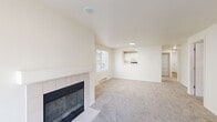 This single-floor residence offers a thoughtfully organized layout with 3 bedrooms and 3 bathrooms. The combined living and kitchen area serves as the heart of the home, anchored by a tile-surround fireplace with a glass front and large sliding glass doors that allow generous natural light and outdoor views. The kitchen features white cabinetry, light countertops, a full suite of white appliances including a dishwasher and range, a stainless steel sink, and warm hardwood-style flooring—complemented by a pass-through window that connects to the living area. Plush carpeting runs throughout the living room, hallway, and all three bedrooms, adding warmth and comfort underfoot. The primary bedroom is generously sized, with a large window providing natural light, and connects to a well-equipped en-suite bathroom featuring dual sinks, a wide vanity with white cabinetry, a large wall mirror with lighted fixtures, and a soaking tub. Additional bedrooms include closets with built-in rods and shelving, and one bedroom features a sliding-door closet with panel doors. Two dedicated closets offer additional storage. The in-unit laundry area houses a full-sized washer and dryer with overhead wire shelving. A carpeted hallway connects all rooms efficiently, making this a highly functional and comfortable residence.