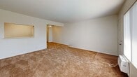 Located at 1130 W Fourth St in Ontario, California, this one-bedroom, one-bathroom residence offers a practical and efficiently organized single-floor layout. The open-concept living area seamlessly combines the living room, dining space, and kitchen into one cohesive zone. The living room is generously proportioned, featuring warm neutral carpeting and a large window fitted with vertical blinds that allow ample natural light to fill the space. A pass-through window connects the living area to the kitchen, which features rich warm-toned wood cabinetry extending to the ceiling for substantial storage, a double-basin sink, and light hardwood-style flooring. White appliances, including a refrigerator and range, complete the kitchen setup. The bedroom is a comfortable, carpeted room with a window that brings in natural light, and is complemented by a dedicated closet with sliding doors. An additional closet elsewhere in the unit provides extra storage. The bathroom includes a full tub-shower combo with clean white tile surround, a toilet, and a frosted window for privacy and ventilation. A hallway connects the rooms, contributing to the overall functional flow of the space. The clean, neutral palette throughout creates a bright and move-in-ready environment.
