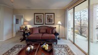 The Bradford floor plan delivers a well-appointed single-level layout featuring two bedrooms and two full bathrooms. The living room serves as the heart of the home, highlighted by crown molding, a ceiling fan, and a sliding glass door that opens to a private balcony, filling the space with natural light and outdoor views. An adjoining dining area with an arched entryway provides an elegant transition into the main living spaces. The kitchen is fully equipped with stainless steel appliances, including a refrigerator, range, and microwave, complemented by granite-style countertops, ample white cabinetry, and wood-style flooring that adds warmth throughout. Both bedrooms offer plush carpeting and ceiling fans, with the second bedroom featuring bright windows that bring in additional natural light. Each bathroom is well-appointed, with one featuring a tub/shower combination, wood-style flooring, and granite-style vanity countertops. A dedicated in-unit laundry area with a full-size washer and dryer adds everyday convenience. Throughout the home, neutral tones, crown molding details, and consistent finishes create a cohesive and comfortable living environment.