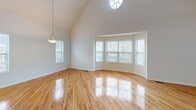 Located at 1 Rosewood Ave in Springfield, NJ, this two-story home offers three bedrooms and three bathrooms thoughtfully distributed across two floors. The main level features a combined kitchen and living room, where the living area immediately impresses with soaring vaulted ceilings, gleaming hardwood floors, and a striking bay window that fills the space with natural light. A wood-railed staircase with an open upper balcony adds architectural character and a sense of openness to the living area. The kitchen is well-equipped with rich cherry wood cabinetry, granite countertops, stainless steel appliances including a gas range and microwave, and a utility room conveniently accessible nearby. Upstairs, the second floor hosts all three bedrooms, two hallways, and a dedicated closet. The spacious primary bedroom features hardwood flooring and a large walk-in closet with wire shelving. Additional bedrooms offer hardwood floors, natural light from double windows, and closet space. The bathrooms are finished with white tile, including one featuring a glass-enclosed soaking tub and shower combination, and another with a standalone glass-door shower, granite-topped vanity, and a window for natural ventilation. The home also includes a utility room on the main level, completing this functional and comfortable residence.