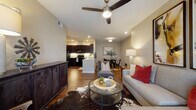 Located at 1151 Mallard Way in Kerrville, Texas, this single-floor residence offers a thoughtfully designed open-concept layout that seamlessly connects the living, dining, and kitchen areas. Rich hardwood-style flooring runs throughout the main living spaces, anchoring the warm, contemporary aesthetic.

The kitchen is a standout feature, outfitted with dark espresso cabinetry reaching to the ceiling, granite countertops, black appliances including a refrigerator, range, and built-in microwave, and under-cabinet lighting that adds a polished touch. A peninsula with bar seating provides a convenient casual dining option. Adjacent to the kitchen, a dedicated dining area offers an intimate space for sit-down meals.

The living room is spacious and inviting, centered around a ceiling fan with a light fixture and recessed lighting. It flows naturally into the dining space, making the layout ideal for everyday living and entertaining.

The bedrooms are carpeted for comfort and feature large windows that invite natural light and offer outdoor views. The primary bathroom is well-appointed with a granite-topped vanity with dark cabinetry, a tub-shower combination, and access to a walk-in closet. Neutral tones throughout the residence create a calm, cohesive atmosphere with a subtle Texas-inspired character.
