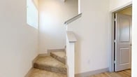 This well-designed multi-story home spans three floors, offering a thoughtful layout with contemporary finishes throughout. The main living area features light hardwood flooring, recessed lighting, and large windows that flood the space with natural light, creating a bright and welcoming atmosphere. The kitchen is a standout feature, boasting granite countertops with a generous island, white cabinetry, stainless steel appliances, and pendant lighting — all complemented by the continuity of light hardwood floors.

The bedrooms are carpeted for comfort, including a spacious primary suite with an en-suite bathroom and a large walk-in closet equipped with extensive wire shelving and a window for natural light. A versatile flex room with soaring ceilings and oversized windows serves well as a home office or additional living space.

The bathrooms are finished with clean white subway tile, granite vanity countertops, light wood-look flooring, and modern fixtures. One bathroom features a glass-enclosed walk-in shower, while another offers a full soaking tub. Carpeted stairs with white wood railings and handrails connect the three levels seamlessly, contributing to the home's cohesive, modern aesthetic.