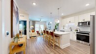 Located at Sawgrass Bay Blvd in Clermont, FL, this well-appointed 2-bedroom, 2-bathroom single-floor home offers a thoughtfully designed open-concept layout. The kitchen is a standout feature, boasting white shaker cabinetry with matte black hardware, quartz countertops, a subway tile backsplash, stainless steel appliances, and a large island with pendant lighting and bar seating — ideal for both cooking and entertaining. The kitchen flows seamlessly into the dining area and living room, where wood-look flooring, a ceiling fan, and a glass-panel door bringing in natural light create a bright and welcoming atmosphere. The primary bedroom is a comfortable retreat with a ceiling fan, natural light from windows, and access to a well-appointed en-suite bathroom featuring a dual-sink vanity with quartz countertops and a glass-enclosed walk-in shower. The second bedroom features distinctive teal accent walls and large windows that fill the space with natural light. Two closets provide generous storage, including a spacious walk-in with wire shelving. A dedicated in-unit laundry room houses a full-size Whirlpool washer and dryer. Wood-look flooring runs throughout the home, tying together a clean, modern aesthetic.