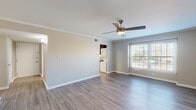 Located at 2112-A Criston Dr in Newport News, Virginia, this well-appointed 2-bedroom, 2-bathroom single-floor home offers a practical and comfortable layout. The spacious living room serves as the heart of the home, featuring wood-look plank flooring, crown molding, a ceiling fan with light fixture, and a large window that invites abundant natural light. The updated kitchen is a functional highlight, equipped with stainless steel appliances including a refrigerator, range, microwave, and dishwasher, complemented by dark cabinetry, granite-look countertops, and a window-facing sink. A stacked washer and dryer unit is conveniently integrated into the kitchen area. Both bathrooms feature tub-shower combinations with white tile surrounds and dark vanities with granite-style countertops. The two bedrooms are carpeted for comfort, offering generous closet space with bi-fold doors and windows that allow natural light to filter in. The primary bedroom is particularly well-sized, providing ample room for furnishings. Neutral tones throughout the home create a clean, move-in-ready atmosphere. A connecting hallway ties all rooms together in a cohesive, easy-to-navigate floor plan.