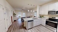 Located at 14110 Paul Howell Road in Northport, Alabama, this 2-bedroom, 2-bathroom single-story residence offers a thoughtfully designed open-concept layout with a clean, modern aesthetic. Wood-look flooring runs throughout the home, lending warmth and continuity to each room.

The kitchen serves as a central hub of the living space, featuring white shaker cabinetry, granite countertops, a peninsula with a stainless steel sink and dishwasher, and stylish pendant lighting overhead. It flows seamlessly into the living room, which is bright and airy, with multiple windows allowing natural light to fill the space. A ceiling fan adds comfort, and an exterior door provides convenient outdoor access.

Both bedrooms are comfortably sized, each equipped with a ceiling fan and direct access to a bathroom. The primary bedroom offers a walk-in closet outfitted with wire shelving for organized storage. The bathrooms feature granite-topped vanities with ample cabinetry, and the full bath includes a tub-shower combination.

A dedicated utility area with additional storage closets rounds out the functional layout. The home's neutral color palette, consistent finishes, and efficient floor plan create a comfortable and cohesive living environment throughout.