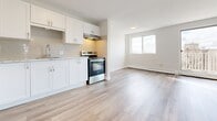 Located at 845 Trillium Park in Sarnia, Ontario, this well-appointed 2-bedroom, 1-bathroom unit offers a clean, modern aesthetic throughout. Light-toned hardwood-style flooring runs seamlessly across the entire space, contributing to a bright and cohesive feel.

The open-concept living and dining area is generously sized, filled with natural light from large windows and a sliding glass door that leads directly to a private balcony with outdoor views. This seamless indoor-outdoor connection makes the living space feel especially airy and open.

The kitchen features white shaker-style cabinetry, a subway tile backsplash, stainless steel appliances including a refrigerator and range, and a built-in range hood — all thoughtfully arranged for efficient use of the space.

Both bedrooms are well-proportioned and bright, each with sliding windows that bring in natural light and views of the surrounding greenery. The spacious primary bedroom also benefits from a sliding door with direct balcony access. Baseboard heating is present throughout.

The full bathroom is finished with large-format tile walls and flooring, and includes a soaker tub with shower, a white vanity with storage, and a round mirror with accent lighting, creating a clean and functional space. Multiple closets near the entry provide ample storage.