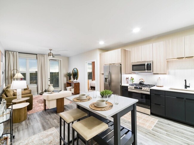 An open-concept apartment home with a central island, streamlined kitchen, and connected living areas designed for everyday flow and flexibility. - Modera Westside Trail