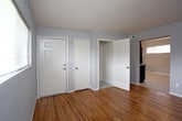 Located at 827 41st Street in Newport News, Virginia, this single-story home offers a straightforward, functional layout with consistent design choices throughout. The interior is finished with cool gray walls and crisp white trim, creating a neutral backdrop that complements the warm-toned hardwood flooring found across the bedrooms and living areas.

The bedrooms are well-proportioned, each featuring natural light from windows with blinds. One bedroom includes two closets — one standard door closet and an additional open closet — offering practical storage. The rooms connect through a central hallway, as visible in the floor plan layout.

The kitchen is a standout feature, presenting a modern aesthetic with rich dark espresso cabinetry, light granite-style countertops, and a full suite of black appliances including a range, dishwasher, and refrigerator. Overhead fluorescent lighting and a window provide ample brightness. Light-toned flooring ties the space together cleanly.

The bathroom maintains the home's neutral tone with light tile-style flooring, a tub-shower combination, grab bar, and a window for natural ventilation. The overall ambiance of the home is clean, updated, and move-in ready, balancing practical utility with modern finishes.