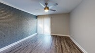 Located at 524 Bramlet Rd in Charlotte, NC, this single-story 2-bedroom, 1-bathroom home offers a thoughtfully designed layout with a blend of modern updates and charming character. The living room serves as a welcoming centerpiece, showcasing a bold painted brick accent wall, durable hardwood-style flooring, a ceiling fan, and vertical blinds that allow for adjustable natural light. The galley-style kitchen is efficiently laid out with white shaker cabinetry, granite countertops, a subway tile backsplash, stainless steel appliances including a dishwasher, range, and refrigerator, and a single-basin sink — all tied together with matching hardwood-style flooring. Both bedrooms feature plush carpeting, ceiling fans with light kits, and windows with blinds that invite natural light. The spacious primary bedroom includes a dedicated closet and access to additional storage, while the second bedroom is equally well-sized. The bathroom features hardwood-style flooring and clean, neutral finishes. A hallway connects the rooms, enhancing the functional flow throughout the home. Neutral gray tones are carried consistently throughout, creating a cohesive and move-in ready atmosphere.