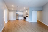 Located at 1600 Genessee Street in Kansas City, Missouri, this modern single-floor unit offers a well-designed open-concept layout with a clean, contemporary aesthetic throughout. Warm hardwood-style flooring runs through the main living and kitchen areas, creating a cohesive and inviting atmosphere.

The kitchen is thoughtfully appointed with white cabinetry, a tiled backsplash, stainless steel appliances including a refrigerator, range, and dishwasher, and a wall-mounted ventilation hood. A sliding barn door adds a stylish architectural touch at the transition between the kitchen and living areas.

The spacious living area benefits from large windows dressed with sheer vertical blinds, allowing ample natural light to fill the room. The neutral gray wall tones complement the bright, airy feel of the space.

The bedrooms feature plush carpeting and generous closet space, including a walk-in closet with built-in wire shelving. The bathroom is well-equipped with a glass-enclosed shower, a white vanity with an undermount sink, and hardwood-style flooring.

A dedicated laundry area houses a full-size washer and dryer alongside additional closet storage, adding practical convenience to this thoughtfully designed home.