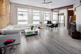 Located at 123 King St in downtown London, Ontario, this one-bedroom, one-bathroom unit blends industrial character with modern finishes across a thoughtfully organized single floor. The open-concept living, dining, and kitchen area forms the heart of the space, distinguished by striking exposed brick accent walls that contrast warmly against crisp white ceilings fitted with recessed lighting and a ceiling fan. Light hardwood-style flooring runs throughout, enhancing the bright, airy atmosphere created by multiple large windows that frame views of the surrounding cityscape.

The living area offers generous room for seating and relaxation, while the adjacent dining zone and dedicated office area provide functional separation within the open layout. The compact kitchen is efficiently designed, featuring stainless steel appliances including a refrigerator, stove, and built-in microwave, complemented by two-tone cabinetry and stone-finish countertops.

The bedroom is an intimate, cozy retreat, also featuring the signature exposed brick wall and a large window with blinds. The full bathroom includes a jetted soaker tub and shower combination, a floating vanity, and clean tile flooring, delivering a polished, modern finish throughout.