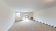 Located at 500 E Main St in Tuckerton, New Jersey, this single-floor unit offers a clean, functional layout designed for comfortable everyday living. The spacious living room is carpeted and filled with natural light, courtesy of a large sliding glass door that opens to a private balcony with outdoor views, complemented by a side window and baseboard heating. The open sightlines from the entry hallway into the living area give the space an airy, welcoming feel. Adjacent to the living room, the kitchen features light wood cabinetry extending along two walls, granite-style laminate countertops, parquet-style flooring, and white appliances including a range and dishwasher, with a built-in microwave overhead. A separate entrance from the living area leads to the bedroom, which is generously sized with plush carpeting and access to a large walk-in closet outfitted with wire shelving on multiple walls. The unit includes two bathrooms: one with a tiled walk-in shower accented by a decorative tile border, and a second full bathroom with a tiled tub-and-shower combination and mosaic tile flooring. The neutral color palette and clean finishes throughout create a bright, move-in-ready environment.