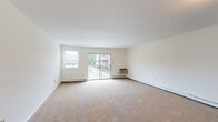 Located at 500 E Main St in Tuckerton, New Jersey, this single-floor unit offers a clean, functional layout designed for comfortable everyday living. The spacious living room is carpeted and filled with natural light, courtesy of a large sliding glass door that opens to a private balcony with outdoor views, complemented by a side window and baseboard heating. The open sightlines from the entry hallway into the living area give the space an airy, welcoming feel. Adjacent to the living room, the kitchen features light wood cabinetry extending along two walls, granite-style laminate countertops, parquet-style flooring, and white appliances including a range and dishwasher, with a built-in microwave overhead. A separate entrance from the living area leads to the bedroom, which is generously sized with plush carpeting and access to a large walk-in closet outfitted with wire shelving on multiple walls. The unit includes two bathrooms: one with a tiled walk-in shower accented by a decorative tile border, and a second full bathroom with a tiled tub-and-shower combination and mosaic tile flooring. The neutral color palette and clean finishes throughout create a bright, move-in-ready environment.